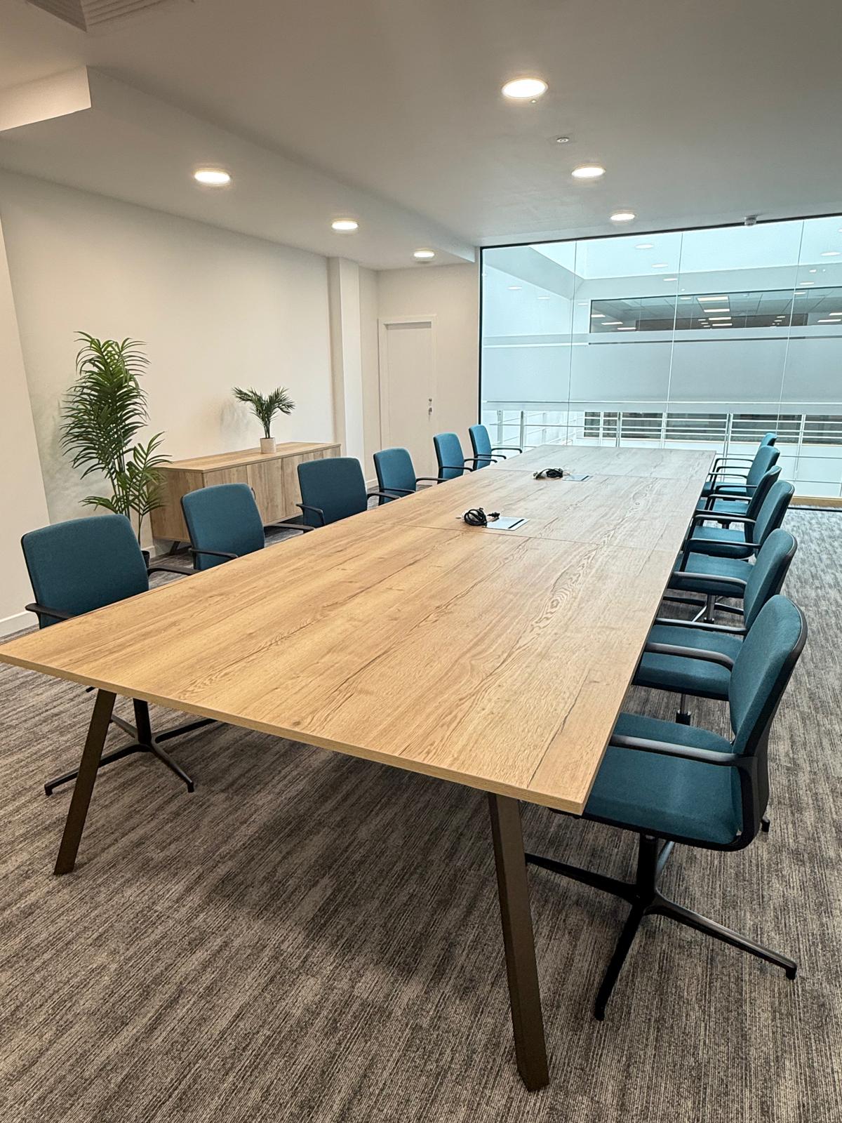 The completed boardroom with a large timber table and teal meeting chairs