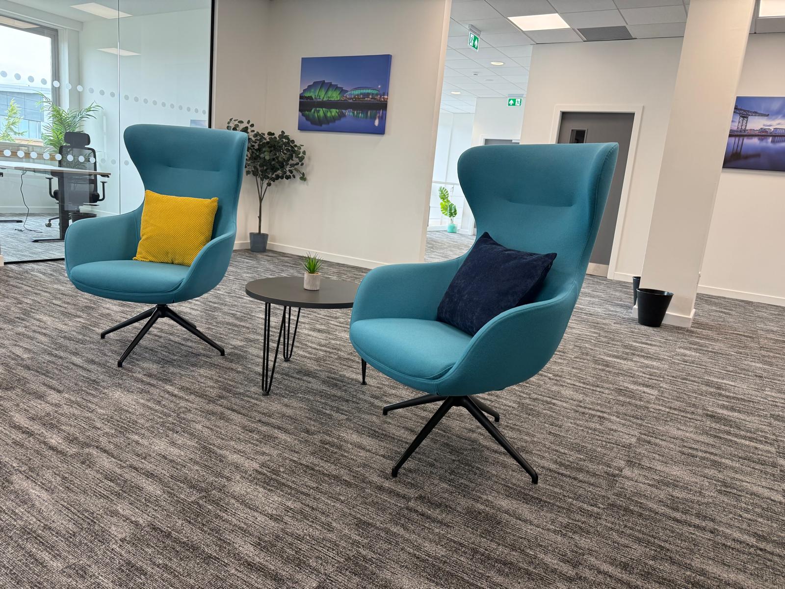 Two teal high-back lounge chairs with accent cushions in a quiet corner