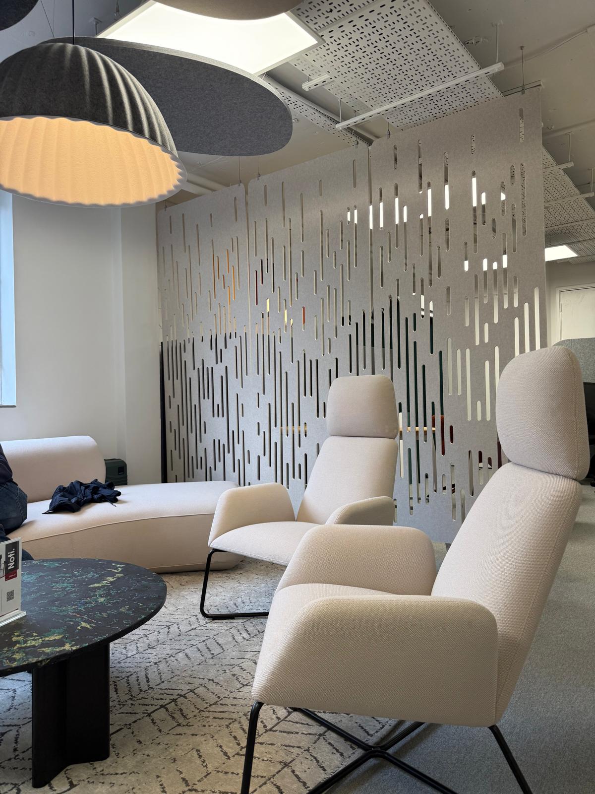 Lounge chairs beside a perforated acoustic room divider