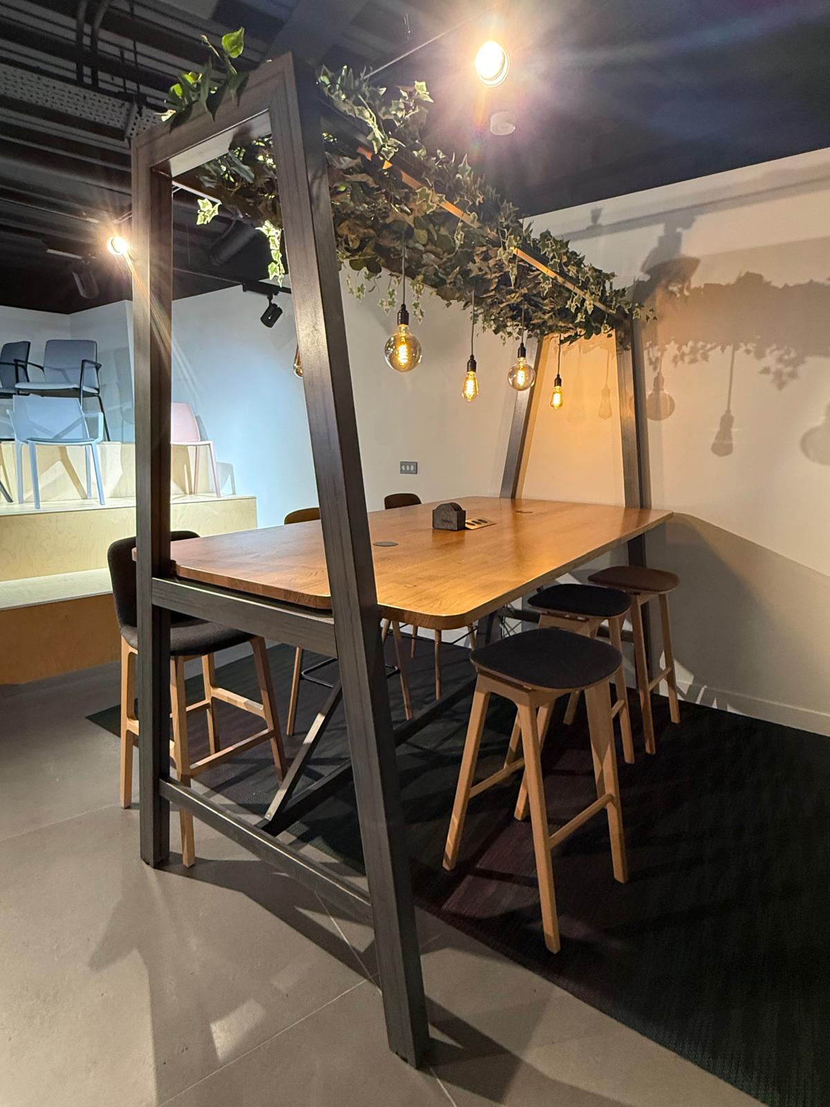 High meeting table under a planted pergola frame with stools