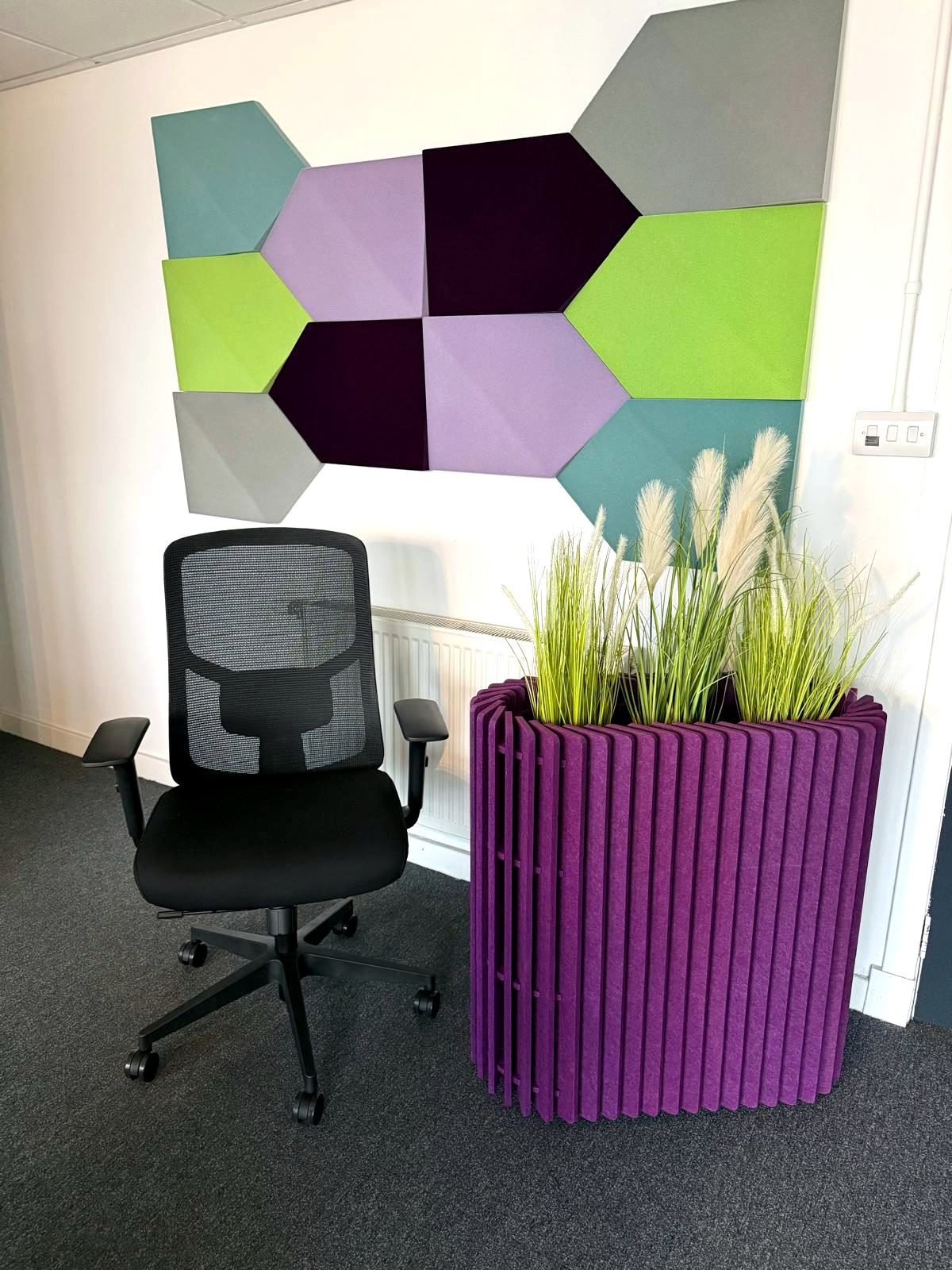 Task chair beside a purple acoustic planter and geometric wall panels