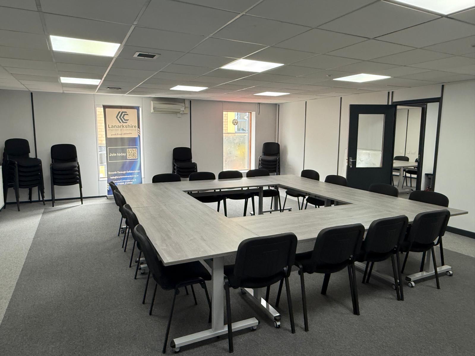 Wide-angle view of the U-shaped conference room with spare chairs stacked along the back wall