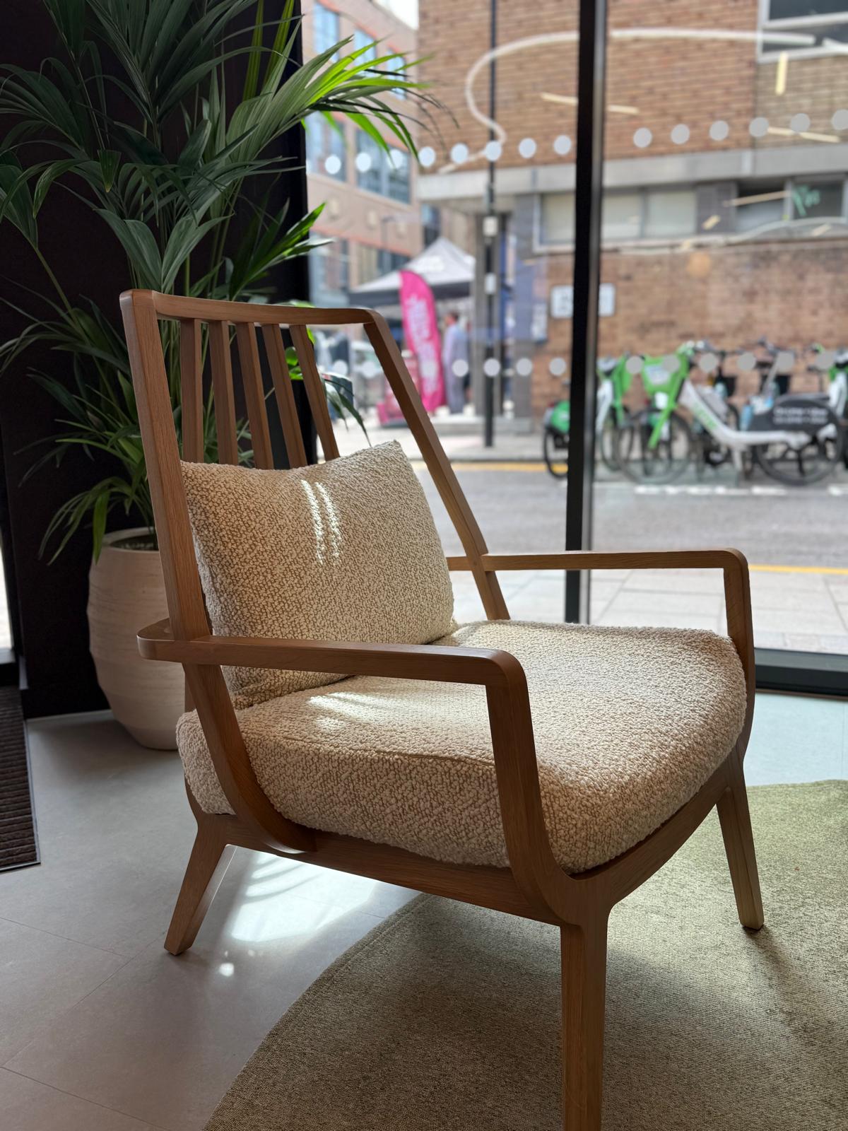 Timber-framed lounge chair with bouclé cushions by a window