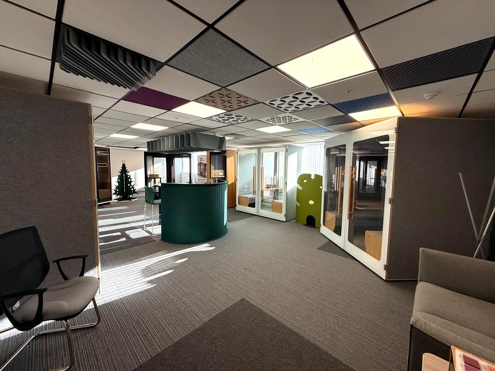 Showroom display of meeting pods, soft seating and a curved collaboration counter