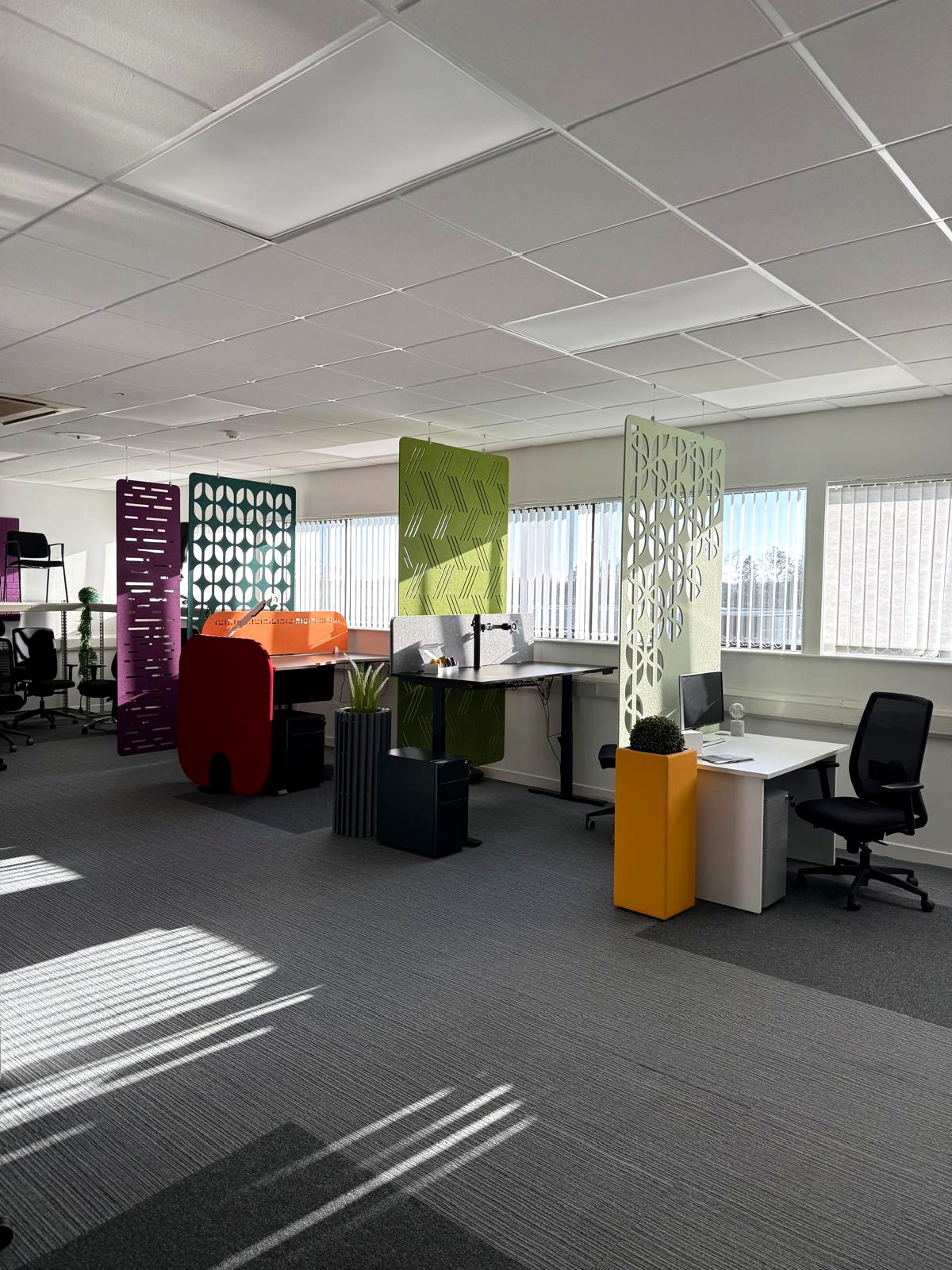 Workstations divided by freestanding patterned acoustic screens