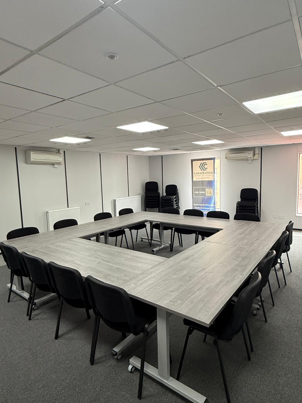 U-shaped conference layout set out with tables and black padded chairs