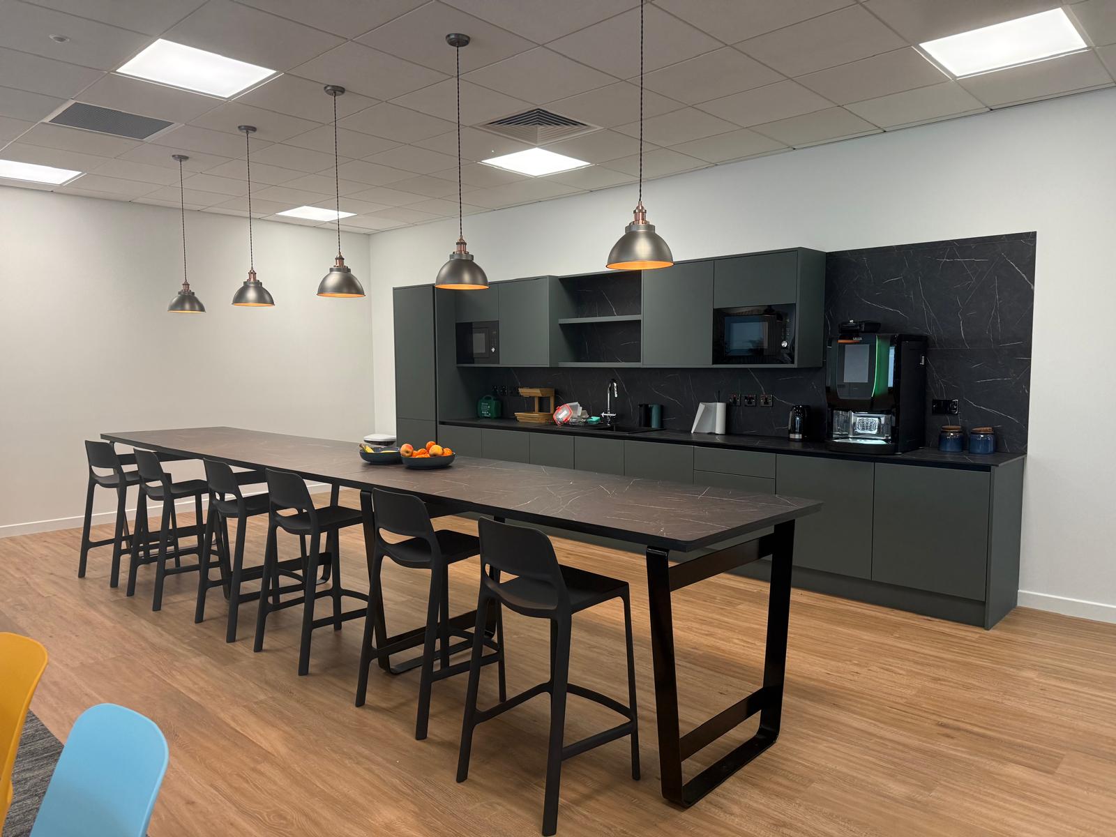 Staff kitchen and dining area with bar-height tables, stools and pendant lighting