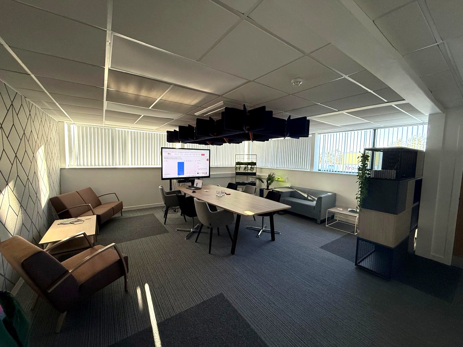 Meeting room with a timber table, lounge seating and suspended acoustic feature