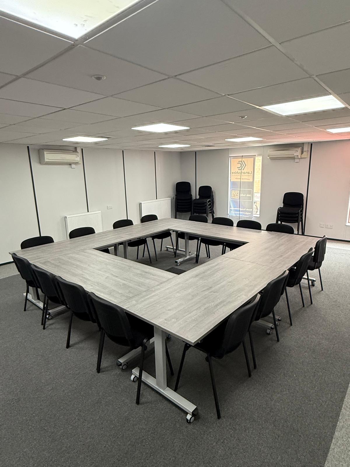Wide view of the hollow-square conference arrangement in the Chamber's meeting room